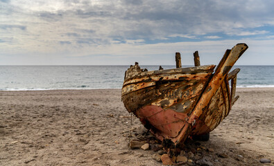 old abandonend beached wooden fishing boat on a beach in Andalusia