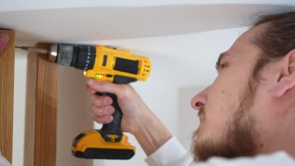 close up. carpenter screws with a screwdriver wooden ash lamellae to the ceiling