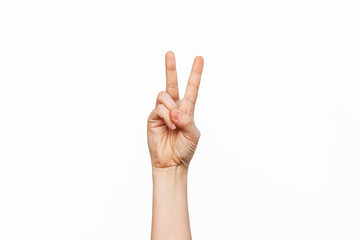 Fototapeta premium A female hand showing a peace gesture isolated on a white background. Victory hand sign