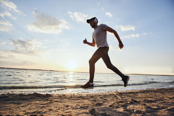Fototapeta na wymiar man in sports clothes running on the evening beach .