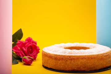 Whole home made pound cake in a studio shot with cheerful, pastel and modern colors set and a flower