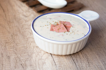 Cheese soup with vegetables and ham with toast on the table close-up horizontal sprinkle oregano in white bowl