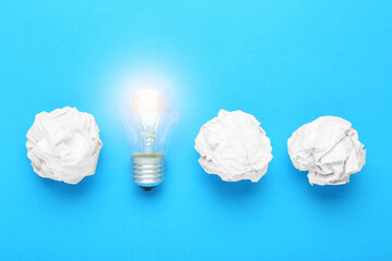 Creative flat lay composition with lightbulb and paper balls on light blue background. Idea concept