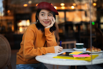 Beautiful Chinese woman drinking coffee in cafe. Young smiling woman enjoy in restaurant..