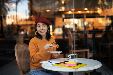 Beautiful Chinese woman drinking coffee in cafe. Young smiling woman enjoy in restaurant..