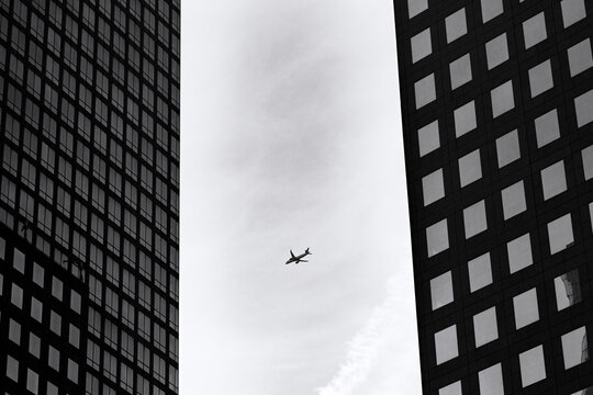 Airplane flying near modern skyscrapers