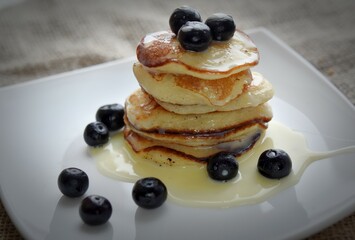 a stack of pancakes with condensed milk and blueberries in a white plate macro