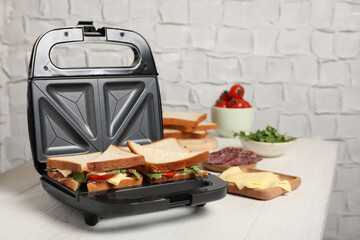 Modern grill maker with tasty sandwiches and ingredients on white wooden table - obrazy, fototapety, plakaty