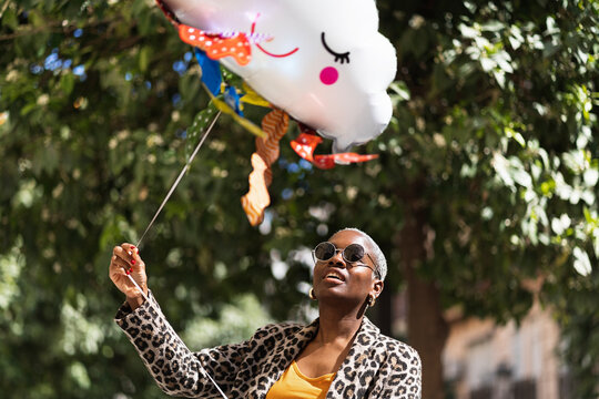 Cheerful black woman with cloud balloon on street