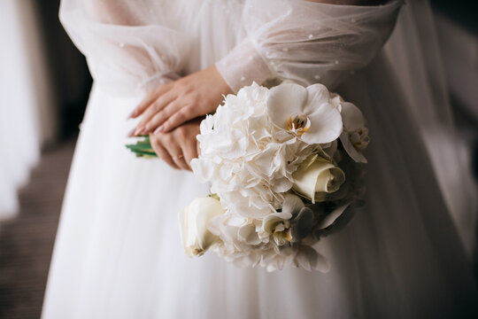 The bride holds in her hands a beautiful wedding bouquet of white orchids