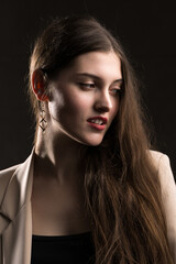 Portrait of a young brunette with long hair in the studio. Dramatic photo in dark colors.