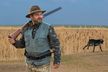 Hunter man in camouflage with a gun during the hunt in search of wild birds or game. Autumn hunting...