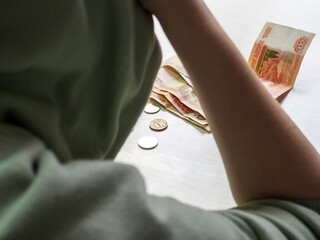 The man is holding his head in front of him on the table with money.  Selective focus.