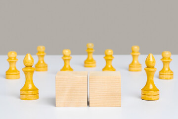 Two wooden cubes with space for text and chess pieces in the background.