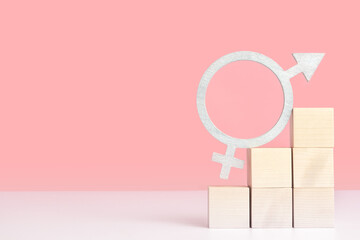 The concept of gender equality, mockup on a pink background with space for text. The symbol of gender equality in silver color stands on wooden cubes arranged in the form of a pyramid ladder