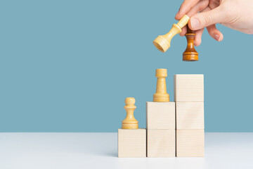 The concept of leadership change and career growth. A hand with a black and a white queen in its...