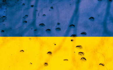 Ukrainian flag with bullet holes on the facade of a residential building as a background. Flag of...