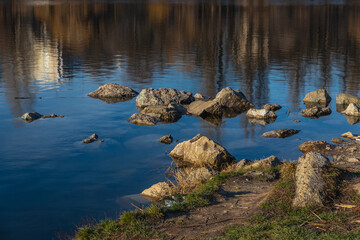 Fototapeta na wymiar Urban landscape. Beautiful view of the city pond. Rocks and reeds on the lake shore in the city.