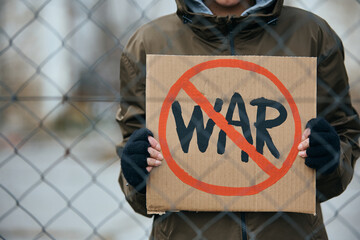 Close-up of anti-war activist behind the barbed wire border with stop war symbol.