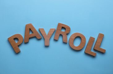 Word Payroll made with wooden letters on light blue background, flat lay