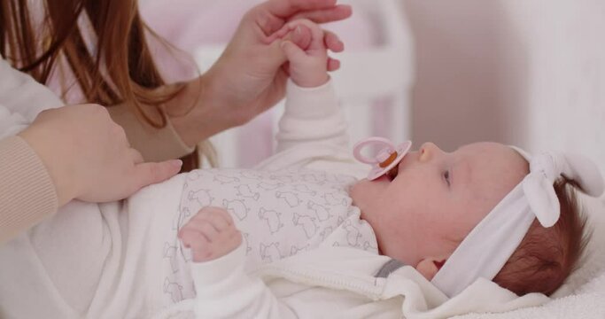 A young mother talks to a newborn baby girl and kisses her tenderly