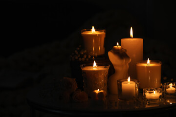 Beautiful burning candles on table in darkness. Space for text