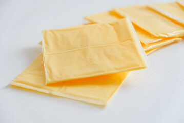 Separately packed cheese slices on a white wooden table background