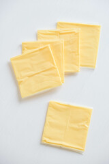 Separately packed cheese slices on a white wooden table background