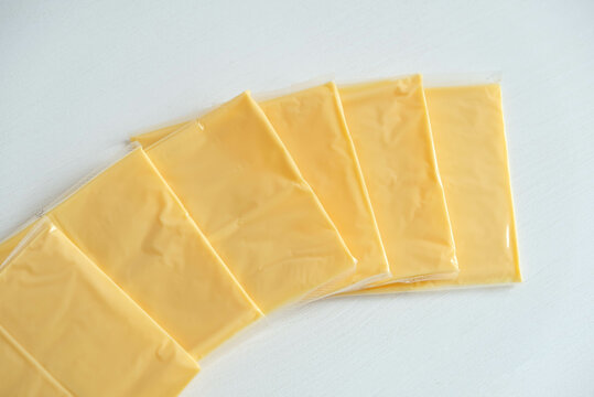Separately packed cheese slices on a white wooden table background