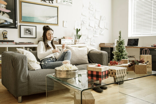 Young woman stringing popcorn Christmas decoration in living room