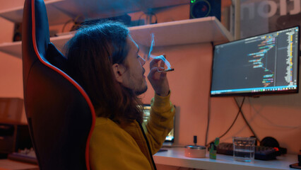 Male IT developer smoking cigarette while working