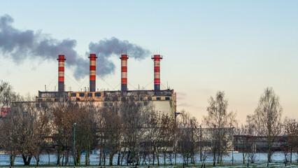 Fototapeta na wymiar Power station with reservoir in winter. Beautiful seaside winter sunset with a smoking factory chimney.