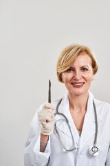 Smiling blonde female plastic surgeon with scalpel