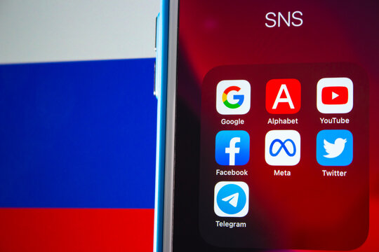 Kumamoto, JAPAN - Mar 1 2022 : Conceptual image of popular SNS or IT company icons (Google, Alphabet inc., YouTube, Facebook, Meta Platform, Twitter and Telegram) on an iPhone with Russian flag.