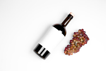 Bottle of wine and grapes on white background, top view, flat lay, composition. Wine degustation mockup concept.