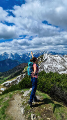 Hiker woman with backpack at summit of Hahnkogel (Klek) with scenic view on mountain peaks in Karawanks and Julian Alps, Carinthia, Austria. Border with Slovenia. Triglav National Park. Spreading arms