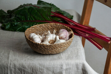 garlic in a bowl of withy and red chard on a linen tablecloth