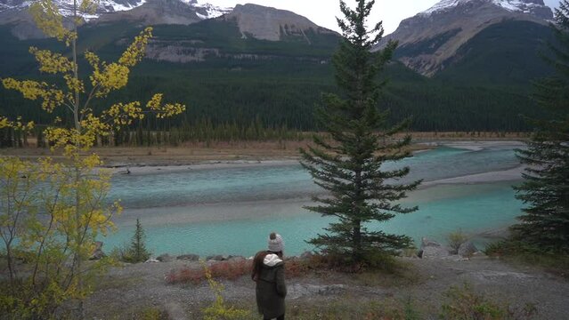 Back of Female Hiker by Glacial Alpine River in Wilderness of Canada. Icefields Parkway Scenic Route, Jasper National Park