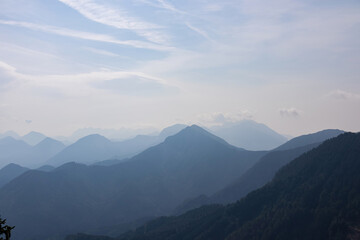 Scenic view on the alpine mountain chains of the Karawanks in Carinthia, Austria. Peaks are shrouded in morning fog. Mystical vibes. Clear and sunny day. Serenity. View from Ferlacher Spitze, Alps