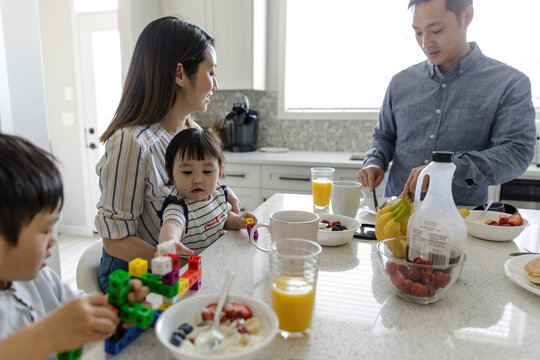 Family eating breakfast and playing with toys in kitchen