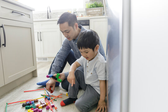 Father and son playing with plastic blocks on kitchen floor