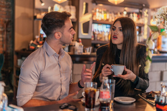 Close up picture of two business colleagues talking in a bar and drinking coffee