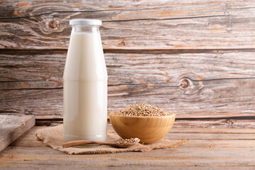 Vegan non diary buckwheat milk in bottle with buckwheat groats and wooden spoon on a wooden...