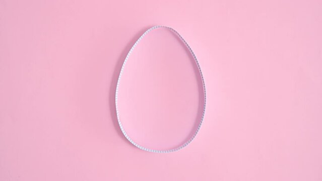 Creative paper egg shape appear on pastel pink background. Flat lay stop motion
