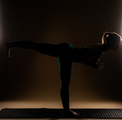 Fototapeta na wymiar Sillhouette of a girl is standing in a yoga pose