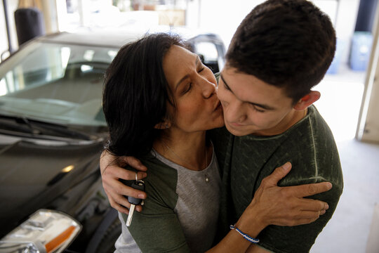 Happy mother and teenage son hugging in garage