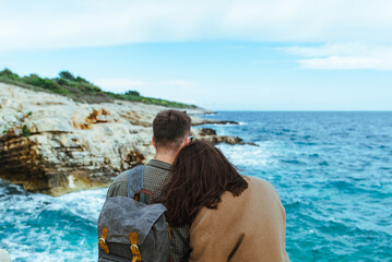 Fototapeta premium couple sitting on the cliff looking at sea