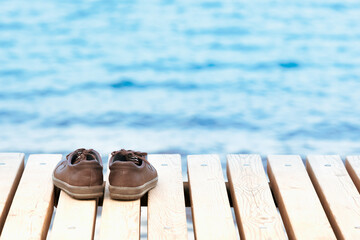 shoes left on a wooden pier against the backdrop of blue water