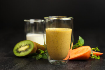 Glass of healthy smoothie with kiwi and carrot on dark background. The concept of healthy eating.