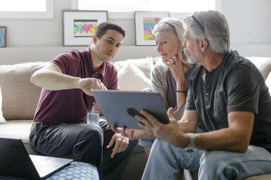 Service Technician Speaking To Senior Couple With Digital Tablet